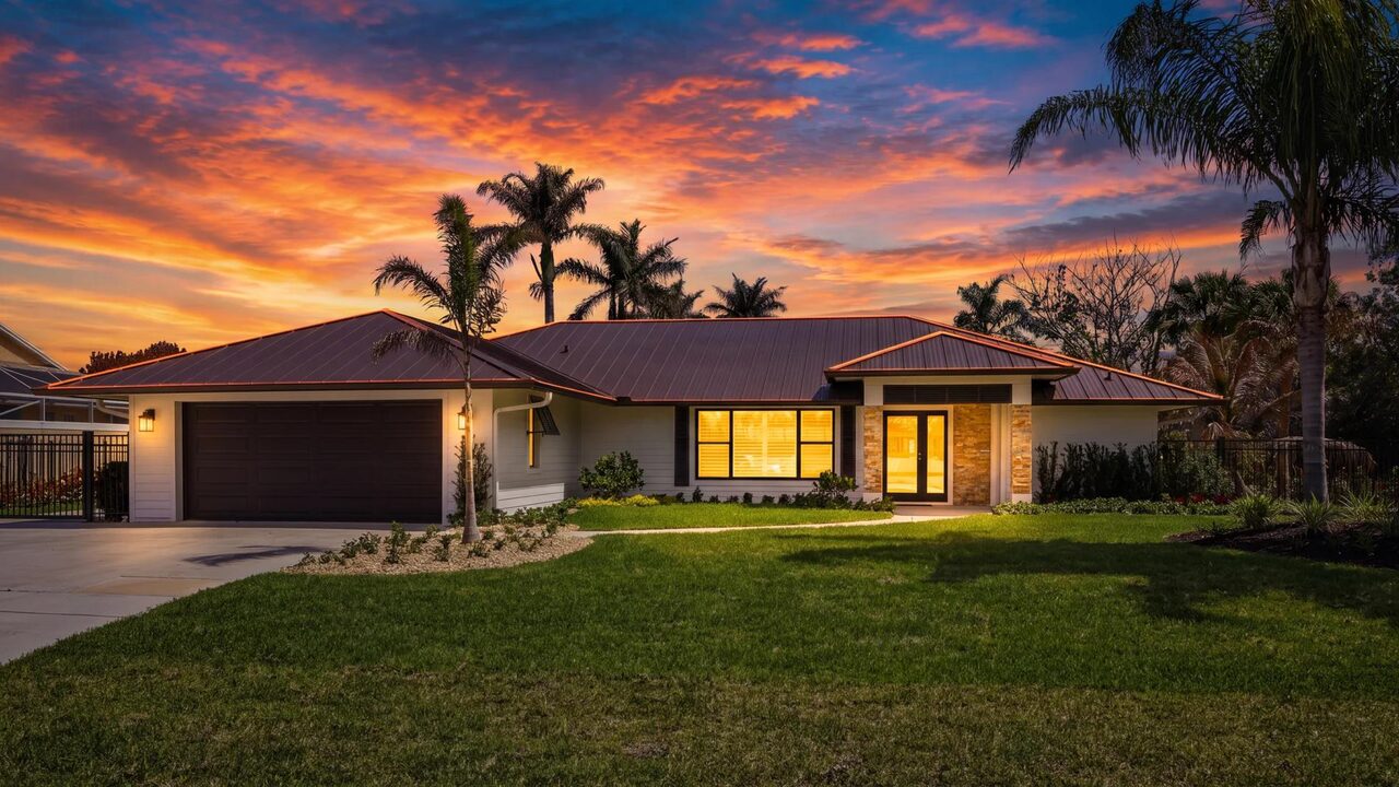 Freshly painted single-story Martin County home at twilight with warm interior lights and palm trees