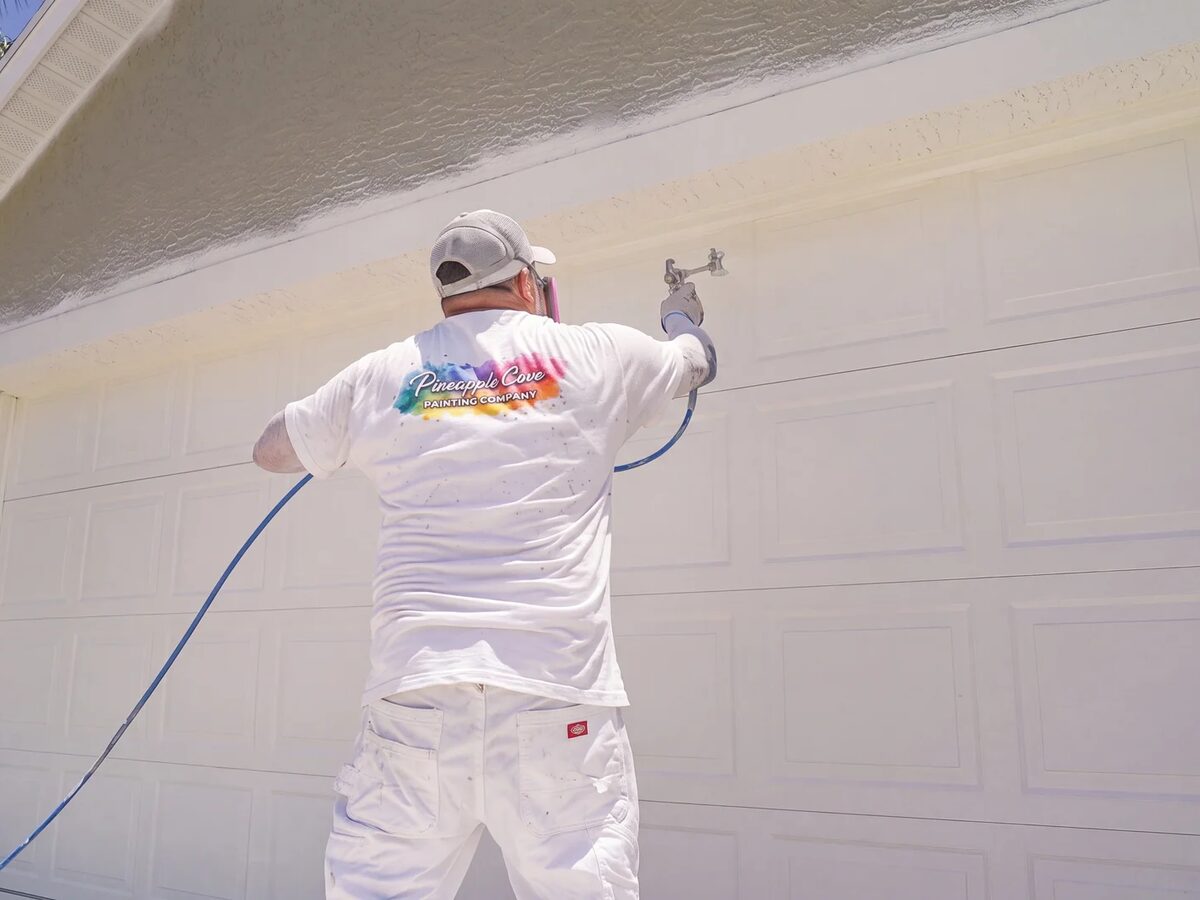 Pineapple Cove Painting crew spray-applying exterior paint on a Treasure Coast home